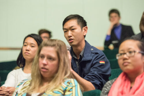 Man in audience speaking into microphone asking a question.